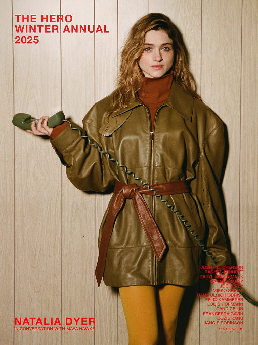 Woman in a green leather jacket holding a weapon against a wooden background, with text about 'The Hero Winter Annual 2025' and 'Natalia Dyer'.